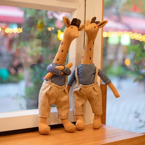 Adorable giraffe plush dolls wearing striped shirts and linen overalls by a window