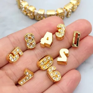 Close-up of 8mm gold rhinestone number charms for DIY jewelry and bracelet accessories.