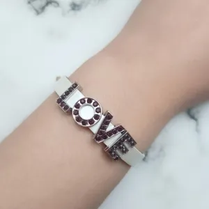 Dettaglio delle lettere LOVE con strass viola brillanti su un cinturino bianco DIY