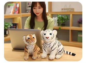 Peluches de tigre realistas en un escritorio junto a un ordenador portátil.