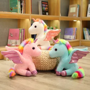Tre peluche di unicorno arcobaleno colorati con ali lucide in una stanza accogliente