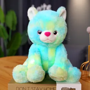 Detail view of a colorful glowing tie-dye cat plush toy sitting on decorative books