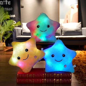 Gros plan de coussins en peluche étoile lumineuse avec LED douces et visages souriants