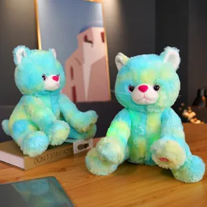 Close-up of cute tie-dye glowing cat plush toys on a wooden table.