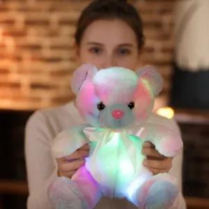 A soft colorful glowing rainbow bear plush toy held by a person as a sweet gift idea