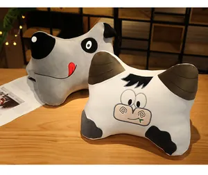 Detailed view of two cute cartoon animal bone-shaped plush pillows on a wooden desk