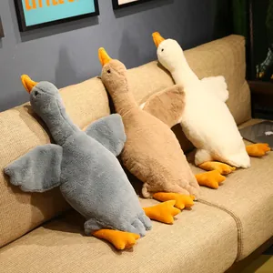 Tres grandes peluches de ganso en gris, marrón y blanco sobre un sofá muy cómodo
