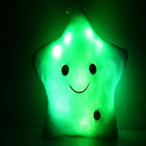 Gros plan d'un coussin étoile en peluche brillant avec des lumières LED vertes dans le noir