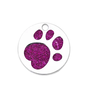 Detailed macro shot showing purple glitter texture on circular metal paw print pet ID tag