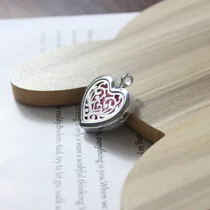 Close-up of a heart-shaped stainless steel locket with intricate hollow-out floral patterns