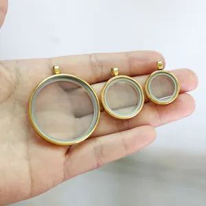 Detailed view of three sizes of round gold-toned glass locket pendants for scale