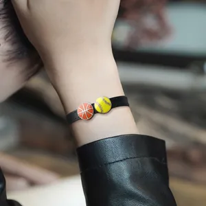 Close-up of 8mm black leather wristband with basketball and softball charms on a wrist