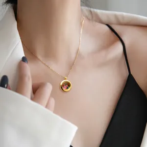 Primo piano della collana con medaglione rotondo in acciaio inossidabile dorato con pietre
