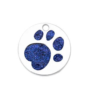 Detail view of round metal pet ID tag with a sparkling blue glitter paw print.