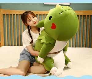 Weiches großes grünes Dinosaurier-Plüschtier, das auf einem Bett gekuschelt wird