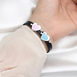 Close-up of heart charms on a black leather strap with LOVE engraving and diamonds.