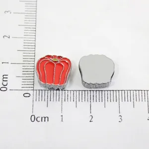 Close-up detail of red bell pepper alloy charm for DIY jewelry making with ruler