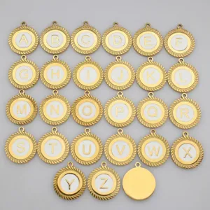 Close-up of gold stainless steel alphabet charms A to Z with white enamel fill.