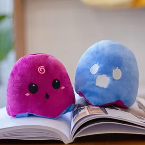 Two reversible luminous ghost plush dolls with cute expressions on an open book