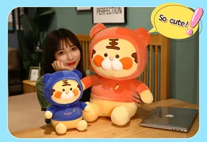 Asiatische Frau hält süße orangefarbene und blaue Tiger-Plüschpuppen mit Kapuzenpullis