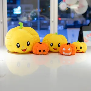 Simpatici peluche di zucca di Halloween in varie dimensioni su una superficie riflettente.