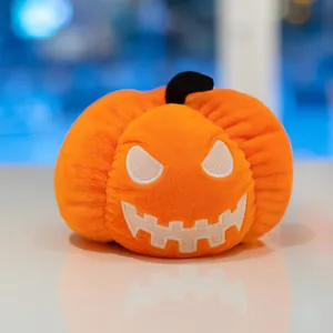 Vista dettagliata di un peluche a forma di zucca di Halloween arancione con ricamo.