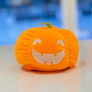 Morbido peluche a forma di zucca di Halloween arancione con viso sorridente ricamato