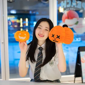 Ragazza sorridente che tiene due simpatici peluche di zucca di Halloween reversibili