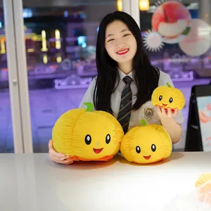 Modella asiatica che tiene tre simpatici peluche a forma di zucca gialla reversibile per Halloween