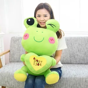 Close-up of a large green cartoon frog plush toy featuring a Love You embroidered heart