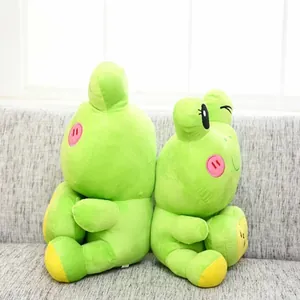 Adorable green cartoon frog plush toy set sitting back-to-back on a soft gray fabric sofa