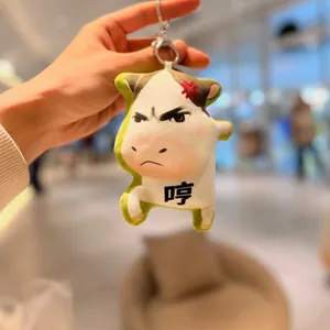 Close-up view of a unique abstract angry cow plush keychain with expressive emoji.