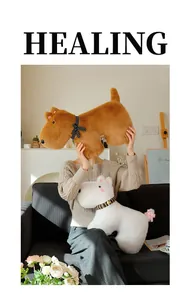 Detailed view of brown and white puppy plush toys held by a model on a sofa