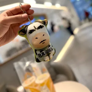 Funny abstract cow meme plush keychain held in hand showing expressive face design