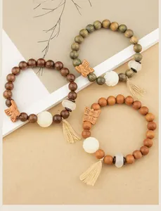 Detail of three Zen-style wooden beaded bracelets with butterfly and lotus charms.