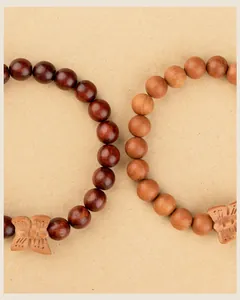 Close-up view of hand-carved wooden butterfly charms on Buddhist prayer bead bracelets