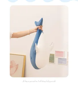 Soft blue whale plush pillow toy held by hand in a cozy bedroom setting for kids gifts