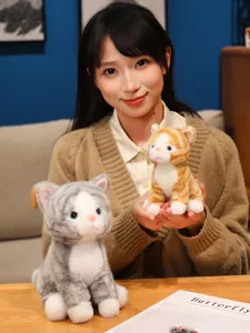 Dettaglio ravvicinato di peluche realistici di gatti tabby grigi e zenzero tenuti da modella