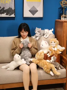 Molti peluche di gatto realistici esposti con una modella asiatica su un comodo divano
