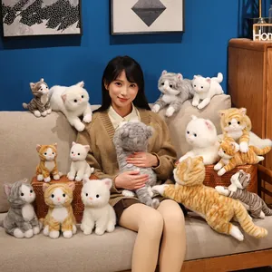 Modella asiatica con una collezione di gatti di peluche realistici sul divano