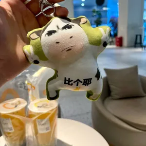 Funny cow plush keychain with meme face expression held in hand as a detail shot.