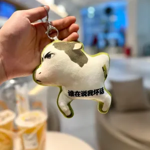 Close-up of a funny grass cow plush keychain featuring an angry expression and Chinese text
