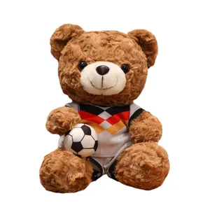 Adorabile orsetto di peluche marrone con maglia da calcio e un piccolo pallone giocattolo