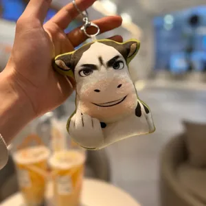 Detailed view of funny cow plush keychain with abstract meme face and middle finger gesture