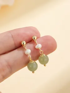 Detailed close-up of elegant gold drop earrings featuring natural Hetian jade and white pearls.