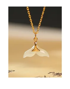 Close-up of elegant gold-plated silver necklace with fishtail-shaped Hetian jade pendant.