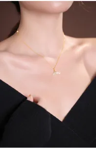 Close-up of a delicate gold fishtail pendant necklace with light green jade detail