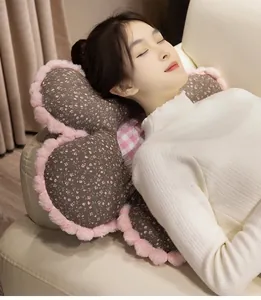 Détail d'un coussin en peluche en forme de fleur avec motif floral et bordure rose douce