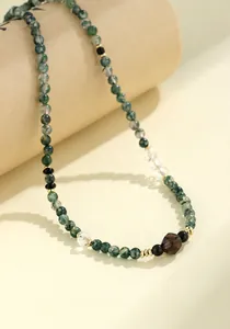 Detailweergave van de natuurlijke mosagaatkralen en gefacetteerde kristallen aan de ketting.