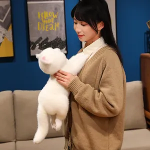 Modella asiatica con un peluche di gatto bianco realistico in un soggiorno.